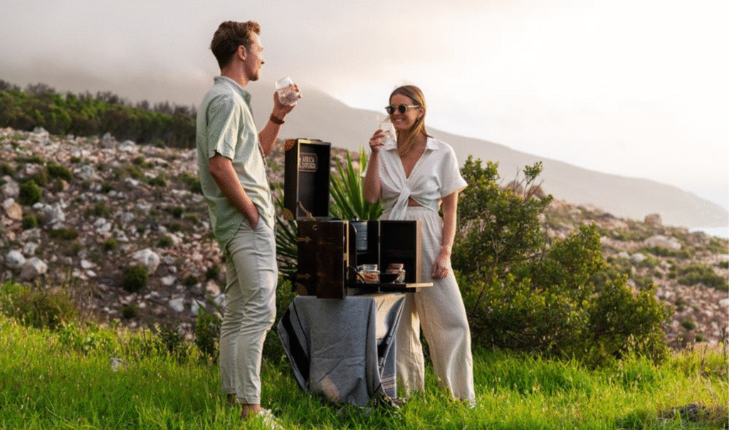 A well-dressed couple enjoying a premium gin & tonic in nature, highlighting a unique luxury Cape Town experience and safari-chic moment.