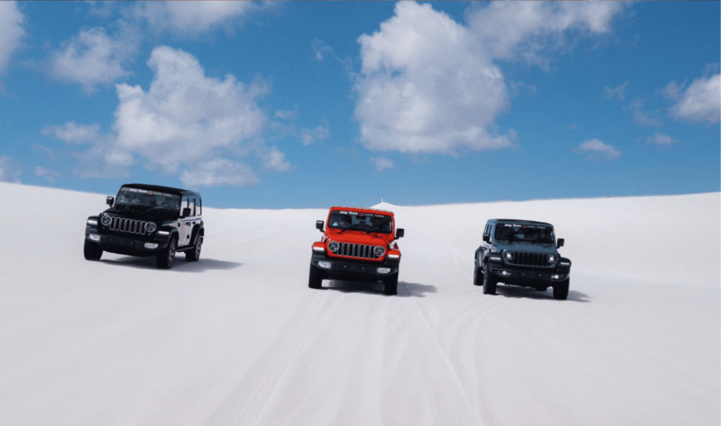 Three 4x4 Jeep Wranglers driving across pristine white sand dunes near Cape Town, showcasing a thrilling off-road luxury adventure.